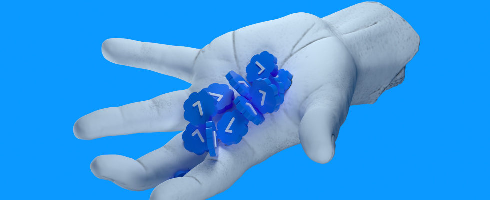 © ilgmyzin - Unsplash, Hand hält weiße Haken in blauen Formen, vor blauem Hintergrund