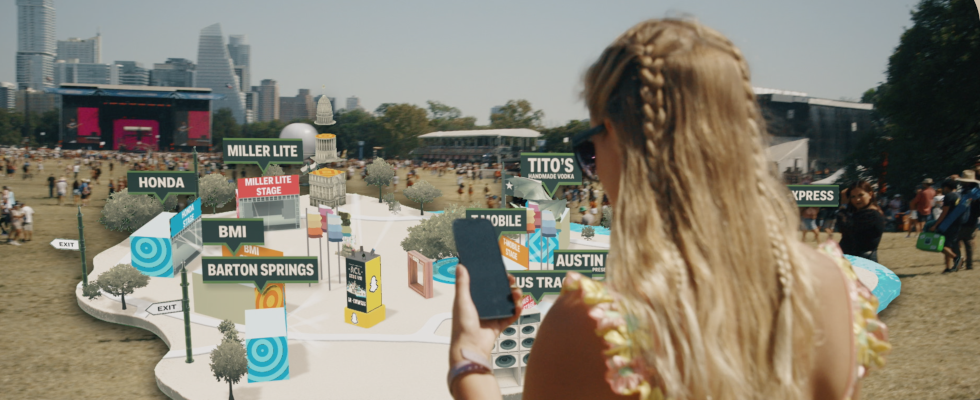 © Snap, Person mit Smartphone vor AR-Landschaft mit Anzeigen, die als Overlay über einem Festivalgelände liegen