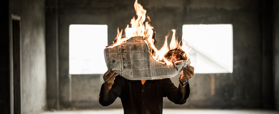 Person hält brennende Zeitung in den Händen
