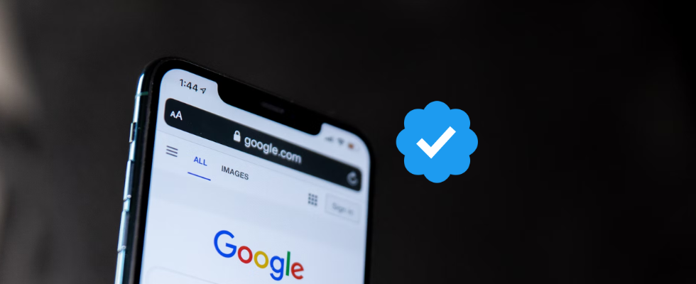 © Solen Feyissa - Unsplash, via Canva, Google-Startseite auf Smartphone, dunkler Hintergrund, blaue Symbol mit weißem Haken darin in der Mitte