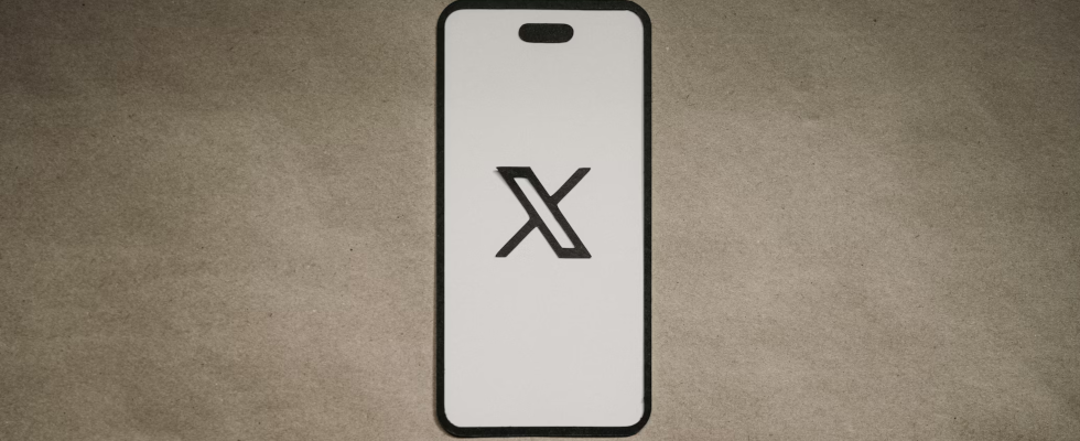 © FLY:D - Unsplash, X-Logo, ausgeschnitten, schwarz auf weißem Hintergrund, Smartphone Mockup, beigefarbener Hintergrund dahinter