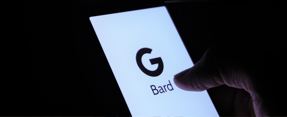 © Mojahid Mottakin auf Unsplash, Hand auf einem Smartphone, auf dem Bildschirm ist das Logo von Googles Chatbot Bard abgebildet. Schwarzer Hintergrund.
