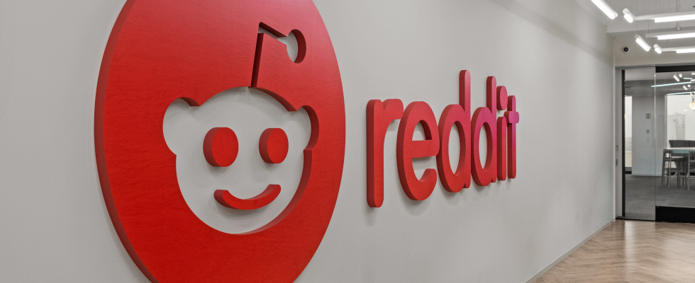 Reddit-Logo und -Schriftzug rot an Wand im Office