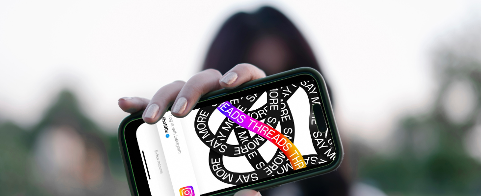 © Viralyft - Unsplash (Änderungen wurden vorgenommen via Canva), Person hält Smartphone mit Threads-Start-Screen in die Kamera, Hintergrund und Person verschwommen