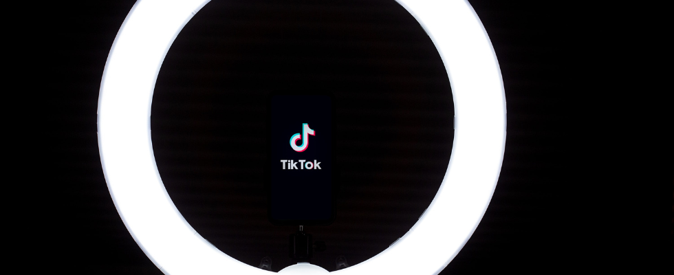 © Solen Feyissa - Unsplash, TikTok-Logo, schwarzer Hintergrund, Ringlicht Hell rund davor