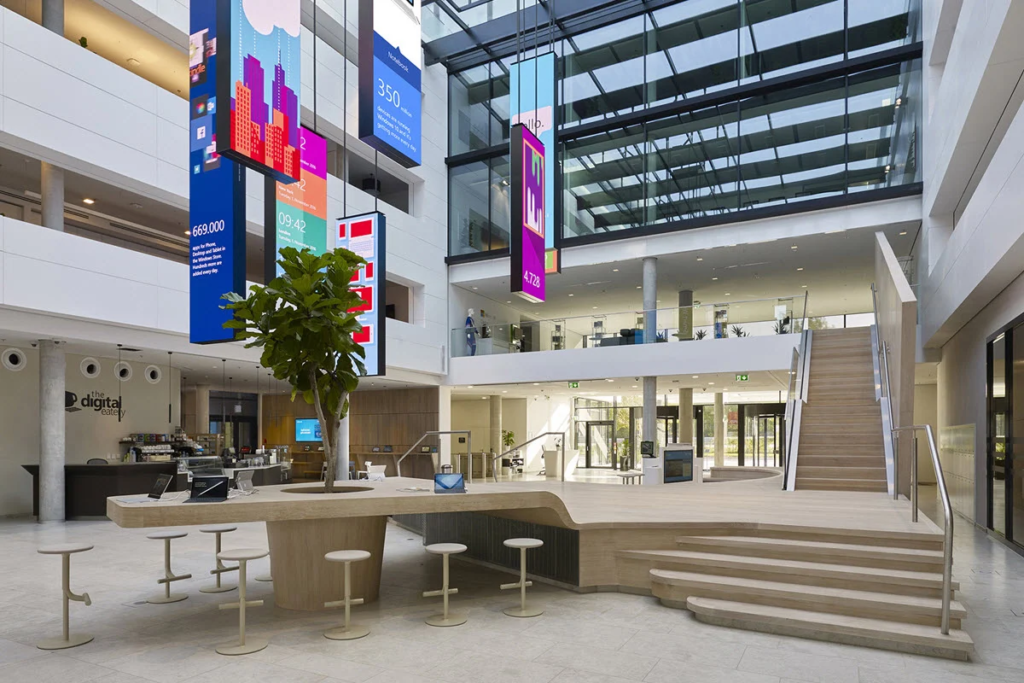 Das Microsoft HQ in München heißt unsere Speaker und Teilnehmer:innen am 10. Oktober willkommen, um in passender Atmosphäre Advertising im KI-Zeitalter zu diskutieren, © Microsoft, Büroeingang mit Treppe, Tisch, Baum, Empfang etc. 