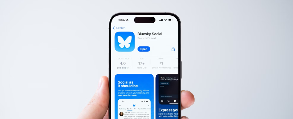 Hand hält Smartphone mit Bluesky App auf Screen