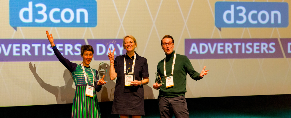 3 Personen mit Lanyards und Trophäen auf Bühne, d3con-Logo im Hintergrund