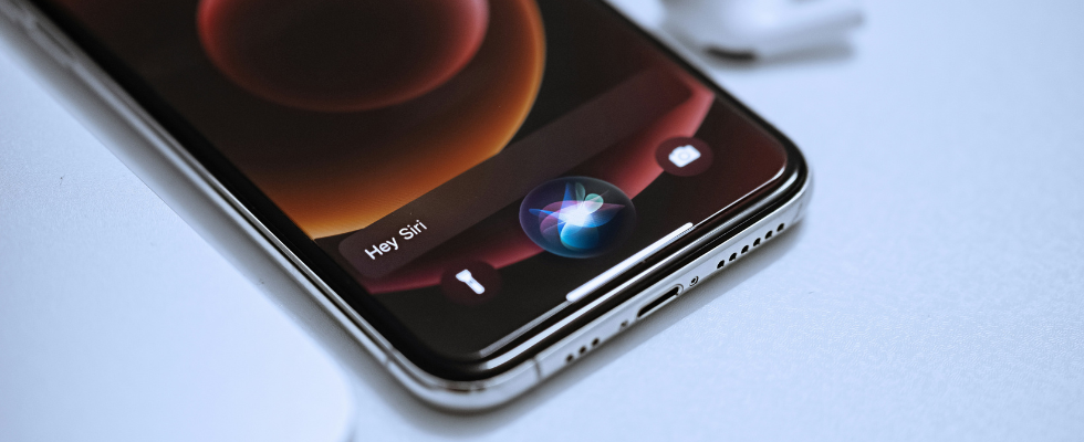 iPhone mit aktivierter Siri-Sprachsteuerung auf dem Bildschirm, Symbol und Text „Hey Siri“ sichtbar.