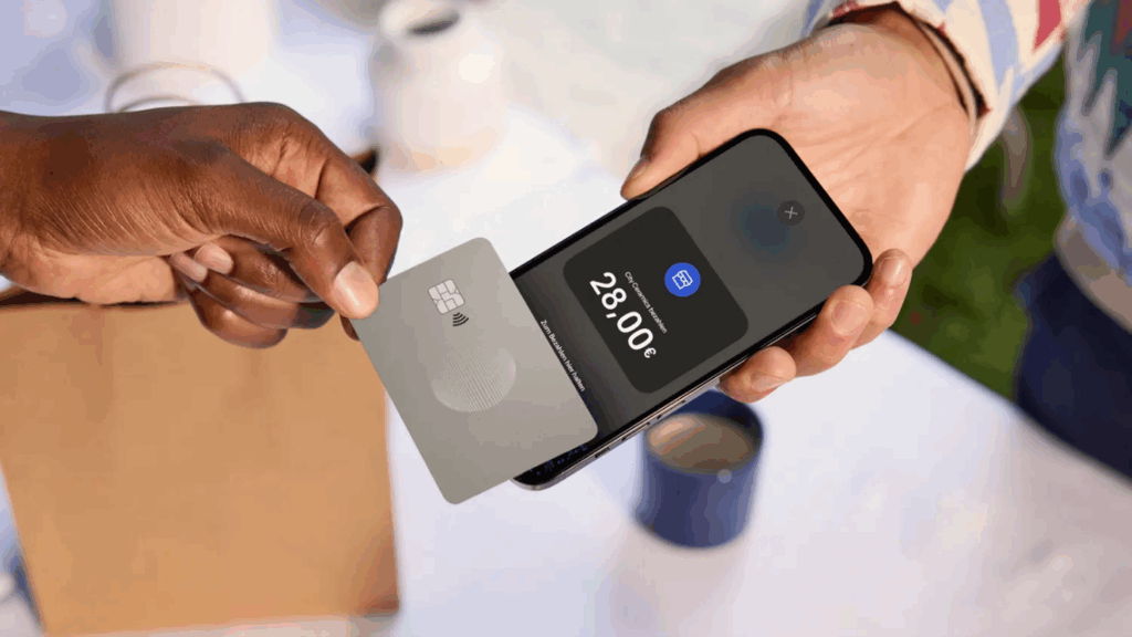 Eine Person hält eine silberne Kreditkarte auf ein Smartphone. Das Display zeigt einen Einkaufsbetrag.