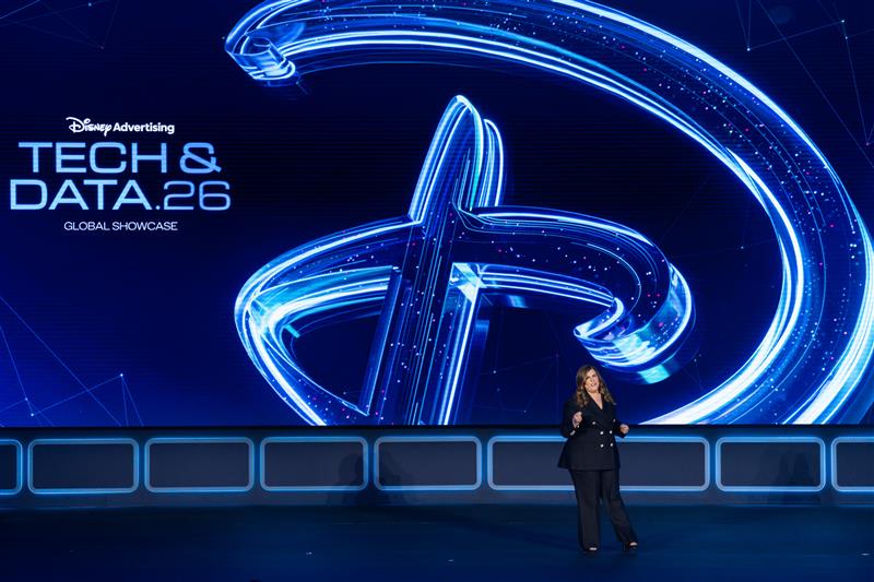 Bühnenpräsentation auf dem Disney Tech & Data Showcase 2026 mit großem leuchtendem Disney-Logo und einer Sprecherin auf der Bühne.