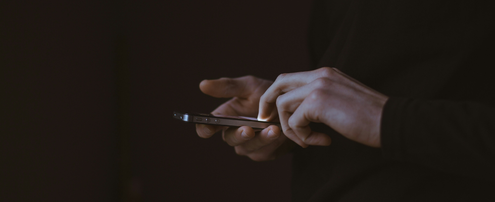 Person nutzt Smartphone im Dunkeln, als Sinnbild für Social-Media-Nutzung und das Urteil zu Plattformmechaniken bei Meta und YouTube.