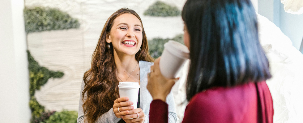 Zwei Frauen trinken gemeinsam auf der Arbeit Kaffee. Übergang zum Artikel: Mehr Arbeit? Wofür eigentlich? Mehr als jede:r 3. zweifelt am Leistungsprinzip